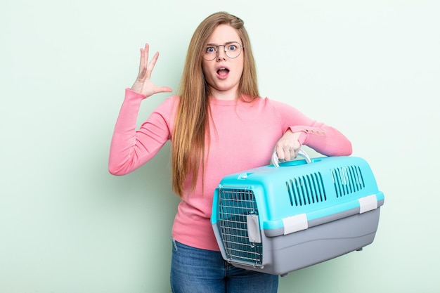 Donna dai capelli rossi che urla con le mani in aria. concetto di trasportino per animali da viaggio