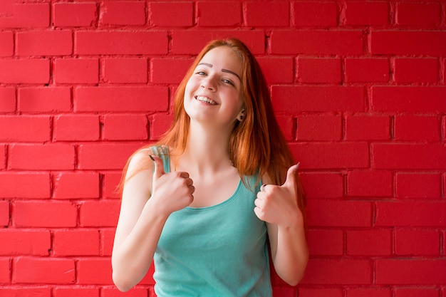 Donna dai capelli rossi sorridente felice che mostra i pollici in su