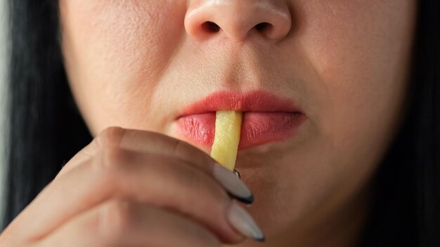 Donna dai capelli scuri che mangia patatine fritte con espressione divertita