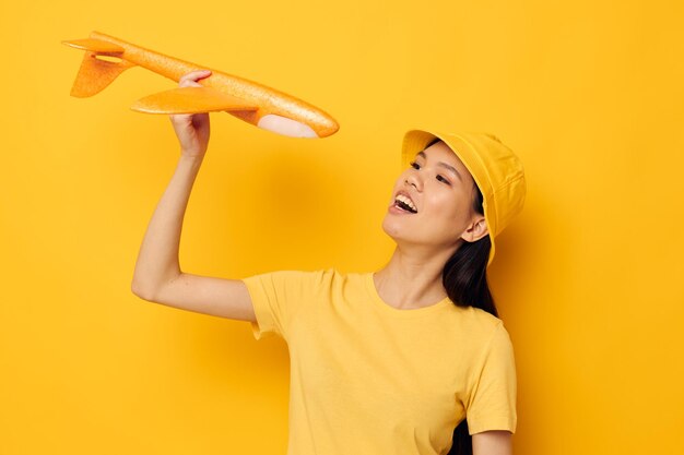 Donna dall'aspetto asiatico con un aereo giallo nelle sue mani uno sfondo isolato giocattolo inalterato