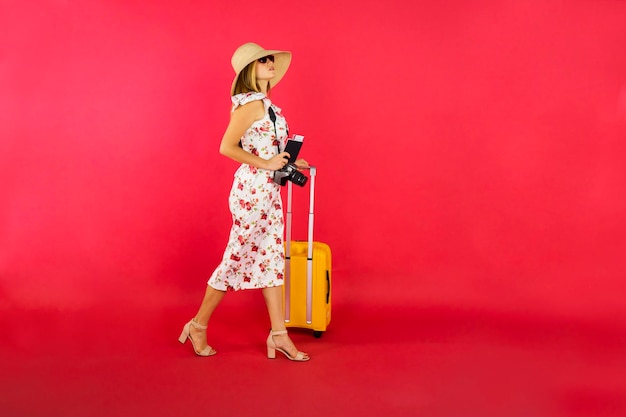 Donna dei capelli biondi che cammina con il passaporto e la valigia
