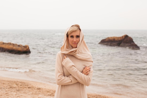 Donna dei pantaloni a vita bassa che cammina sulla spiaggia sabbiosa vicino al primo piano del mare