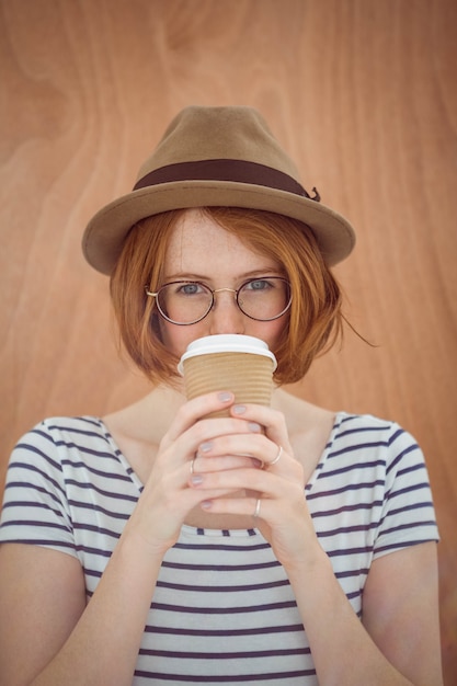 Donna dei pantaloni a vita bassa con capelli rossi che beve caffè