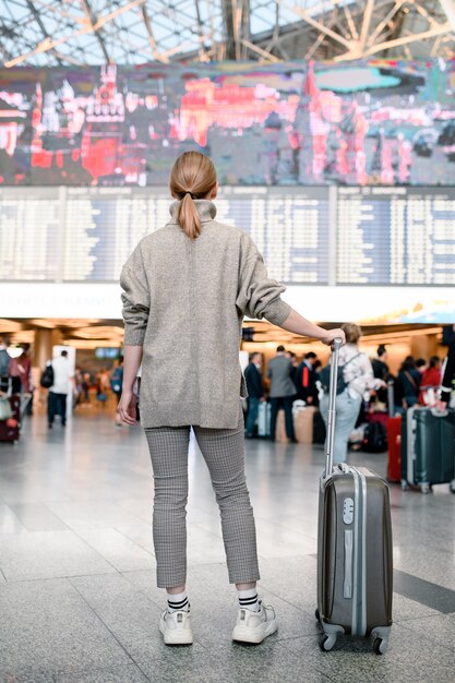 Donna dei viaggiatori che cammina con un bagaglio al terminal dell'aeroporto