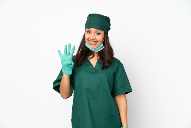 Donna del chirurgo in uniforme verde isolata sulla parete bianca felice e contando quattro con le dita