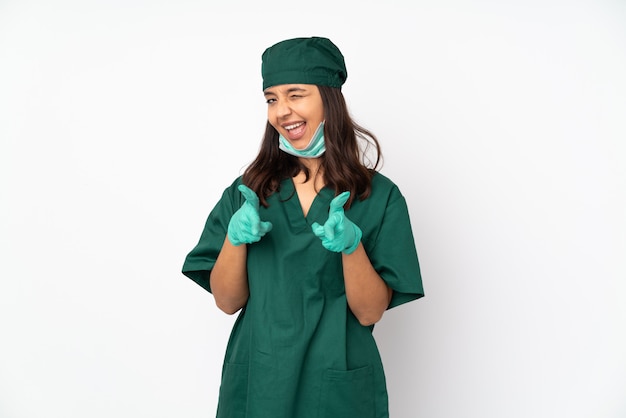 Donna del chirurgo in uniforme verde sulla parete bianca che indica la parte anteriore e sorridere