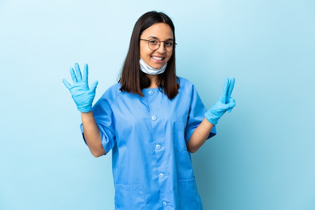 Donna del chirurgo sopra la parete blu che conta sette con le dita