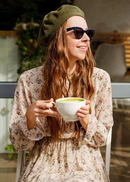 Donna del colpo a metà che tiene la tazza del latte di matcha