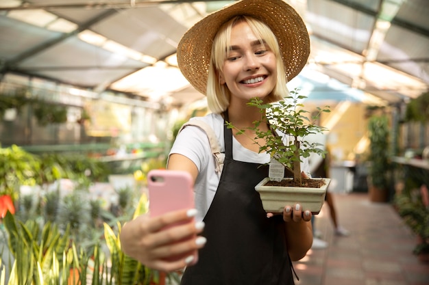 Donna del colpo medio che prende selfie con la pianta