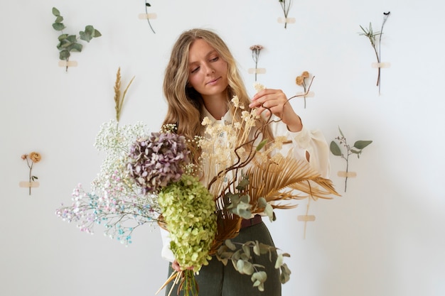 Donna del colpo medio che tiene fiori secchi