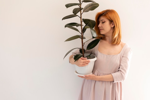 Donna del colpo medio che tiene il vaso di fiori