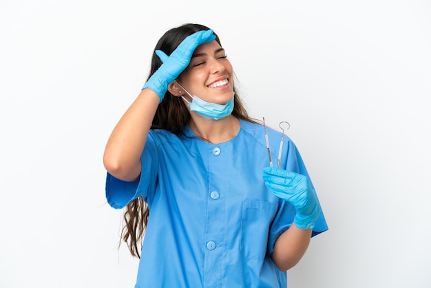 Donna del dentista che tiene gli strumenti su sfondo bianco isolato sorridendo molto