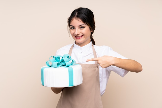 Donna del pasticcere che tiene una grande torta e che lo indica