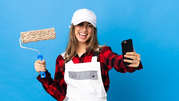 Donna del pittore sul blu isolato che fa un selfie