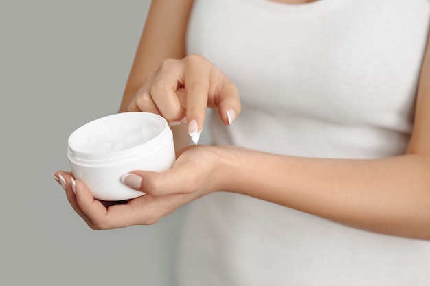 Donna del primo piano che applica crema protettiva sulle mani. Cura della pelle delle mani. Crema cosmetica. Concetto di bellezza e cura del corpo