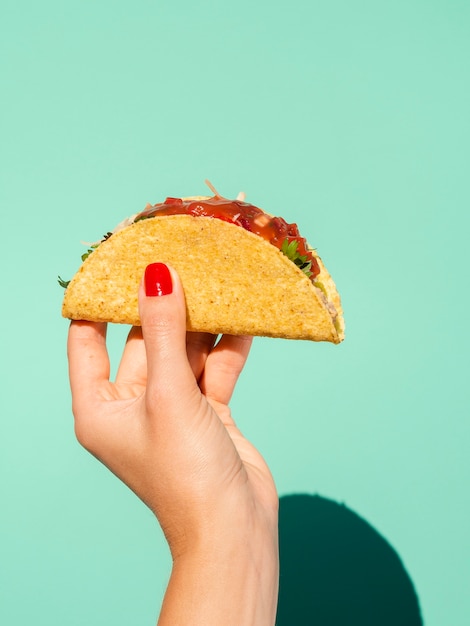 Donna del primo piano con taco e fondo verde