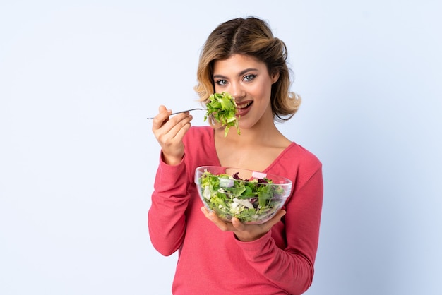 Donna dell'adolescente con insalata isolata sull'azzurro