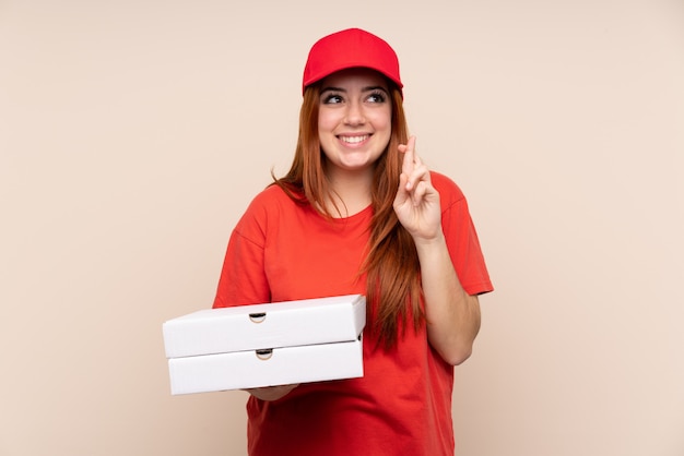 Donna dell'adolescente di consegna della pizza che tiene una pizza con l'incrocio delle dita