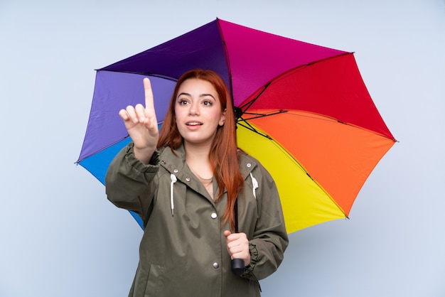 Donna dell'adolescente di Redhead che tiene un ombrello che tocca sullo schermo trasparente