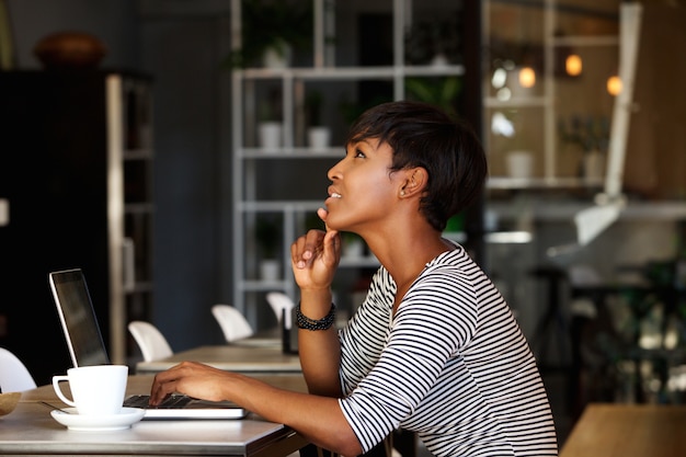 Donna dell&#39;afroamericano che si siede al caffè con il computer portatile