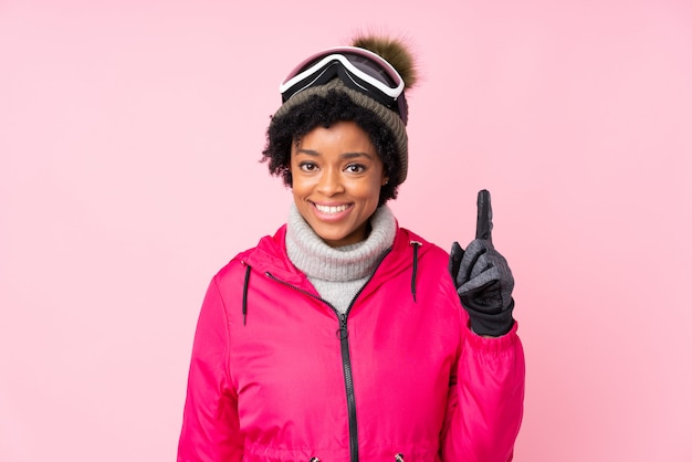 Donna dell'afroamericano con gli occhiali di protezione della neve sopra la parete dentellare