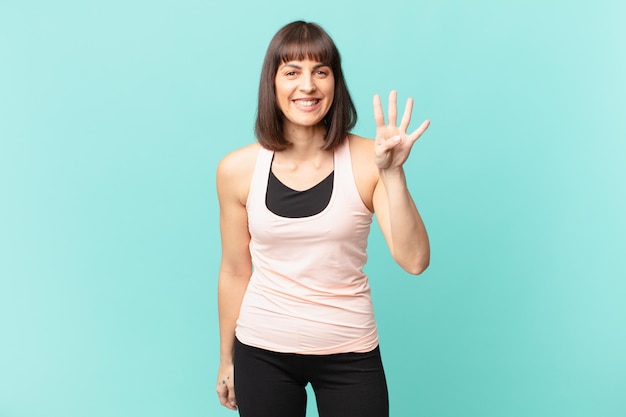 Donna dell'atleta che sorride e che sembra amichevole che mostra il numero quattro o il quarto con il conto alla rovescia in avanti della mano