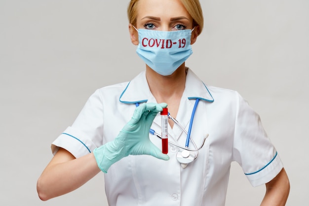 Donna dell'infermiere di medico che indossa maschera protettiva e guanti che tengono la provetta dell'analisi del sangue del virus