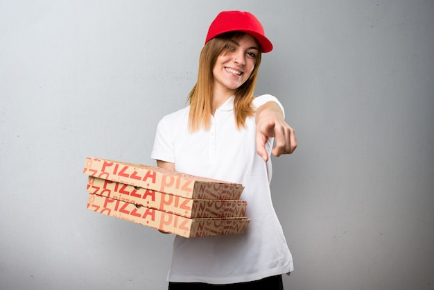 Donna della consegna della pizza che indica la parte anteriore su priorità bassa strutturata