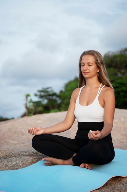 Donna della foto a figura intera che medita su stuoia di yoga