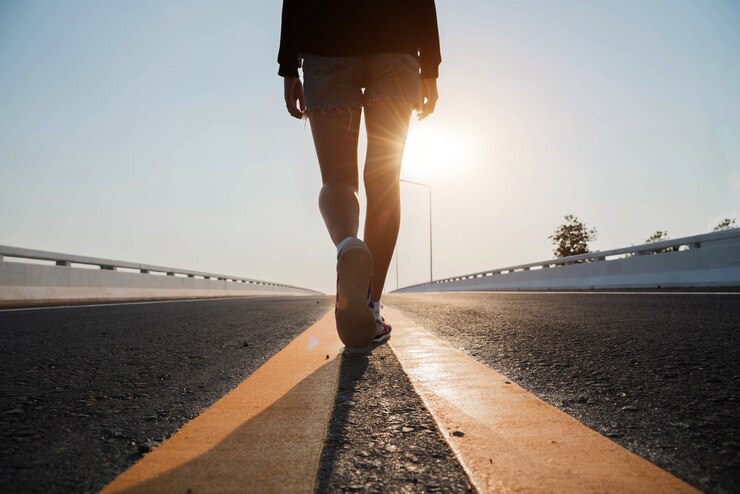 Donna della siluetta che cammina sulla strada al tramonto.