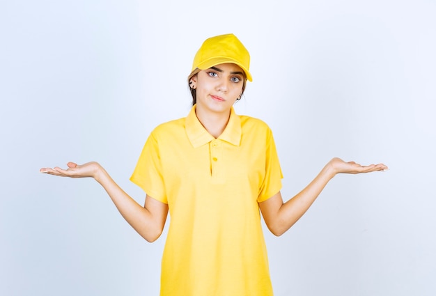 Donna delle consegne in uniforme gialla in piedi e alzando le braccia.