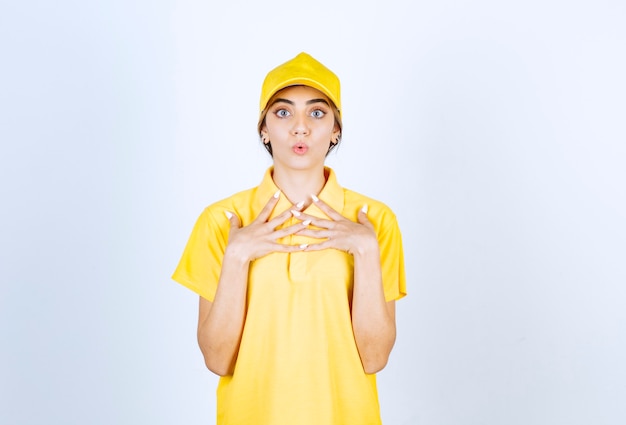 Donna delle consegne in uniforme gialla in piedi e che guarda l'obbiettivo sorprendentemente.