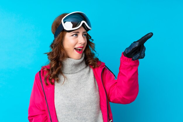 Donna dello sciatore con i vetri di snowboard che indica via