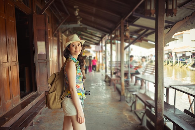 Donna dello shopping che cammina nella strada della terra del mercato galleggiante di Damnoen Saduak, Thailandia. shopping con i fornitori locali negozio negozio visualizzazione di prodotti storici durante le vacanze in Asia con la famiglia in vacanza.