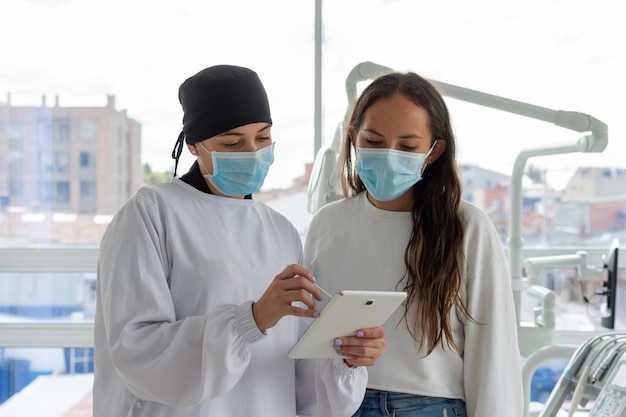 Donna dentista con una tavoletta in mano che spiega a un paziente il trattamento Concetto di clinica dentale