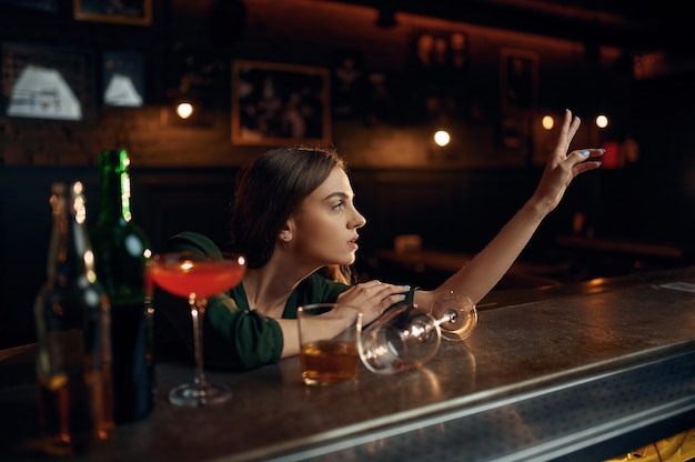 Donna depressa beve alcolici al bancone del bar