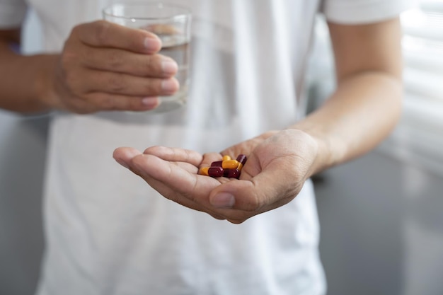 Donna depressa che tiene un bicchiere d'acqua che soffre di mal di testa che combatte lo stress con la vista del primo piano degli antidepressivi