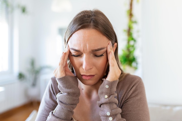 Donna depressa sconvolta che sente forte mal di testa emicrania triste stanco sonnolenza esausta donna che riposa