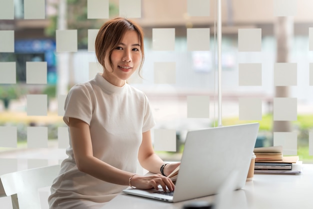 Donna di affari asiatica che lavora al computer portatile in ufficio.