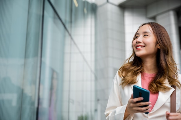 Donna di affari asiatica che manda sms al lavoro di pendolarismo dello smartphone