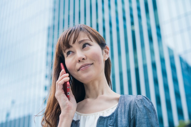 Donna di affari asiatica che per mezzo del telefono