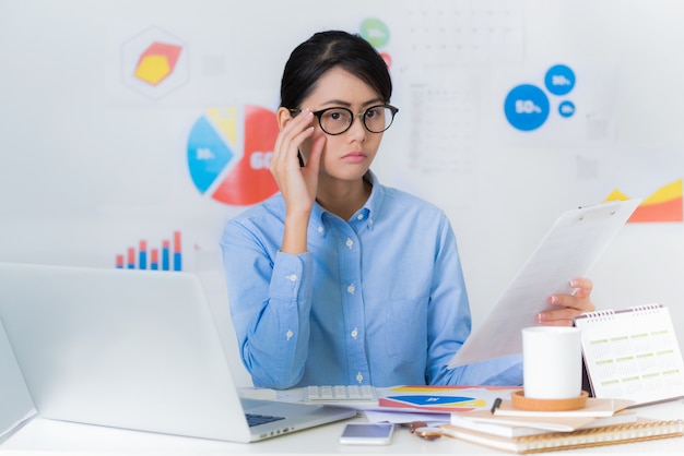 Donna di affari asiatica curiosa mentre lavorando