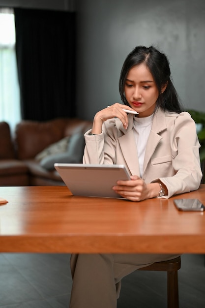 Donna di affari asiatica professionale che si concentra sui suoi compiti di affari sul suo tablet