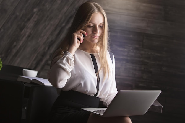 Donna di affari attraente che per mezzo del computer portatile