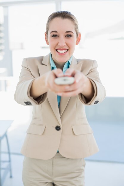 Donna di affari attraente che tiene un sorridere sorridente allegramente alla macchina fotografica