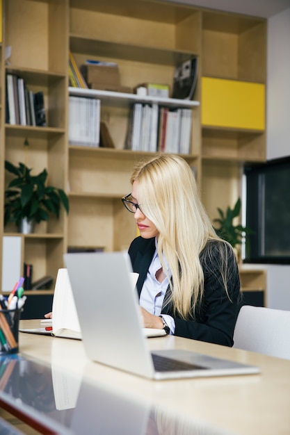 Donna di affari bionda attraente che lavora nell&#39;ufficio moderno