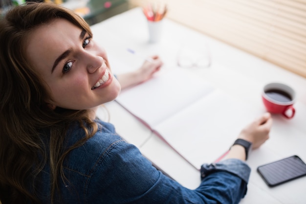 Donna di affari casuale che lavora al suo scrittorio in ufficio