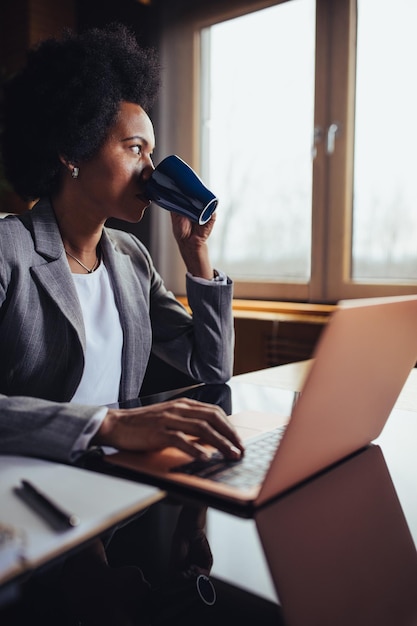 Donna di affari che beve caffè mentre lavora in ufficio