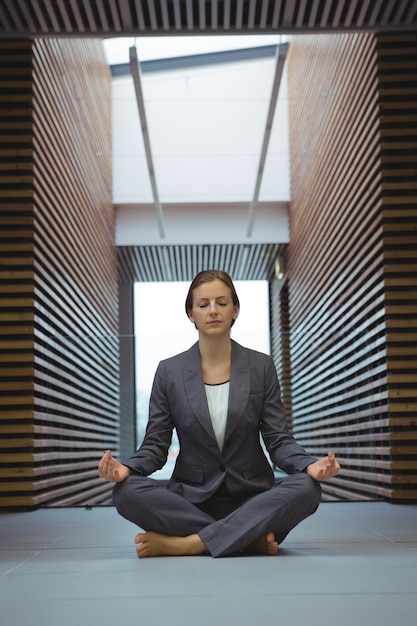 Donna di affari che esegue yoga nel corridoio