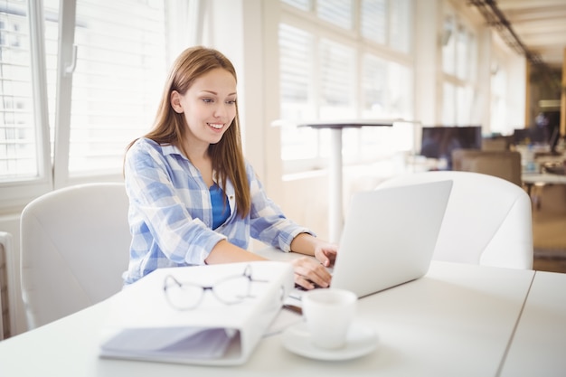 Donna di affari che lavora al computer portatile allo scrittorio in ufficio creativo